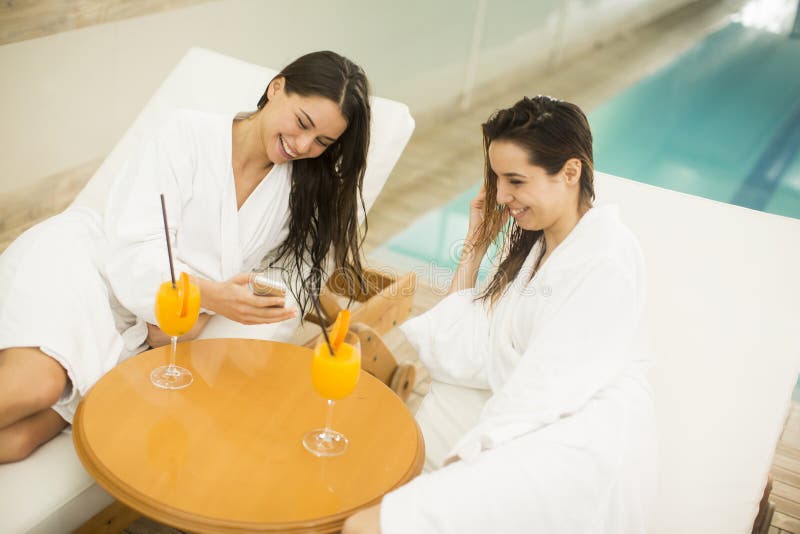Atrakcyjne młode kobiety relaksuje w zdroju pije jui w bathrobes zdjęcia stock Atrakcyjne młode kobiety relaksuje w zdroju pije jui w bathrobes zdjęcia stock