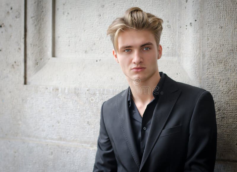 Atrakcyjny blond młody człowiek w kurtce, przeciw ścianie