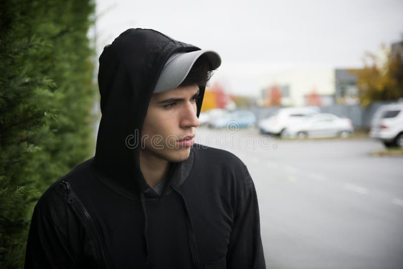 Atrakcyjny młody człowiek z hoodie i baseball nakrętką w mieście zdjęcia stock Atrakcyjny młody człowiek z hoodie i baseball nakrętką w mieście zdjęcia stock