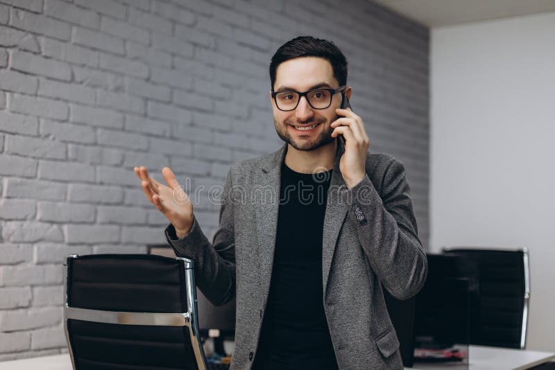 Atrakcyjny przystojny młody brunet brodaty uśmiechnięty wykonawczy pracownika mężczyzna w biurowej pracy stacji miejsce pracy na zdjęcia stock Atrakcyjny przystojny młody brunet brodaty uśmiechnięty wykonawczy pracownika mężczyzna w biurowej pracy stacji miejsce pracy na zdjęcia stock