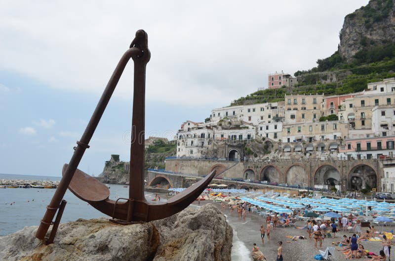 ATRANI, ITALIA, IL 28 GIUGNO 2014: Dettaglio sull'ancora con la spiaggia del atrani dietro La gente è rilassantesi e prendente il fotografia stock ATRANI, ITALIA, IL 28 GIUGNO 2014: Dettaglio sull'ancora con la spiaggia del atrani dietro La gente è rilassantesi e prendente il fotografia stock