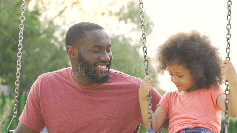 Att bry sig denamerikan fadern som svänger hans lilla dotter, lycklig familjhelg arkivfilmer