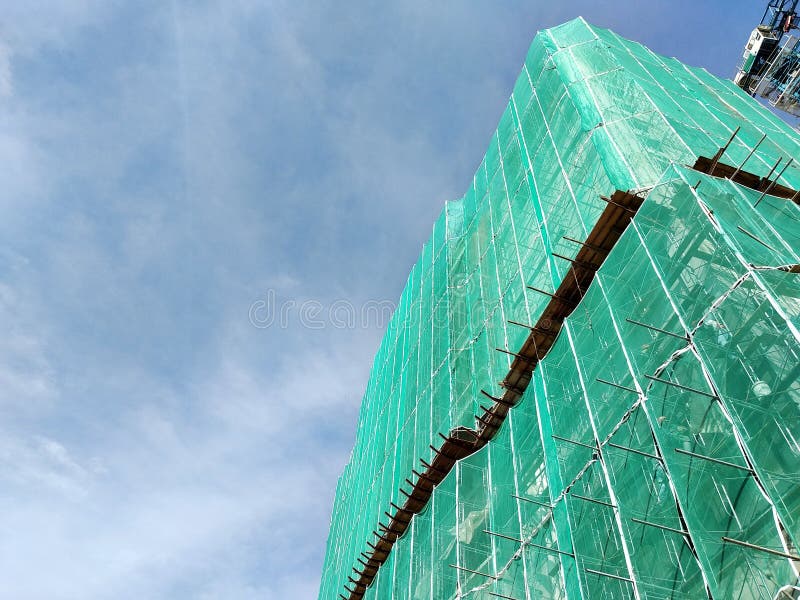 KUALA LUMPUR, MALAYSIA -JULY 16, 2018: Safety netting is installed at the high rise building exterior scaffolding during construction. It is to avoid the waste of building materials falling directly to the ground and causing damage.