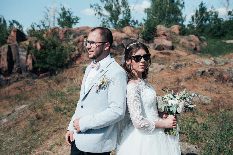 Att gifta sig den fotografiinnegrejbruden och brudgummen i solglasögon på naturen på vaggar royaltyfri bild Att gifta sig den fotografiinnegrejbruden och brudgummen i solglasögon på naturen på vaggar royaltyfri bild