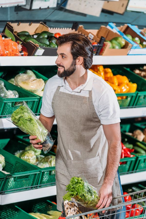 att le shoppar assistenten som ordnar nya grönsaker arkivbild att le shoppar assistenten som ordnar nya grönsaker arkivbild