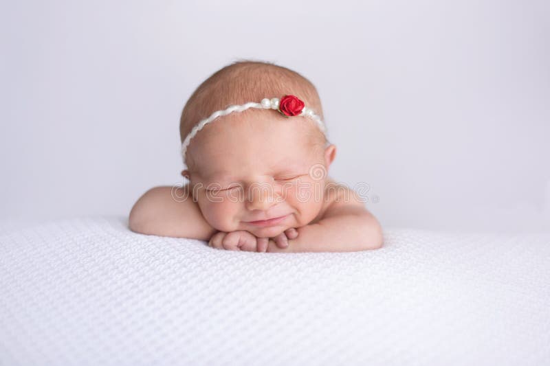 Att le som är nyfött, behandla som ett barn flickan som bär en röda Rose Headband royaltyfri foto