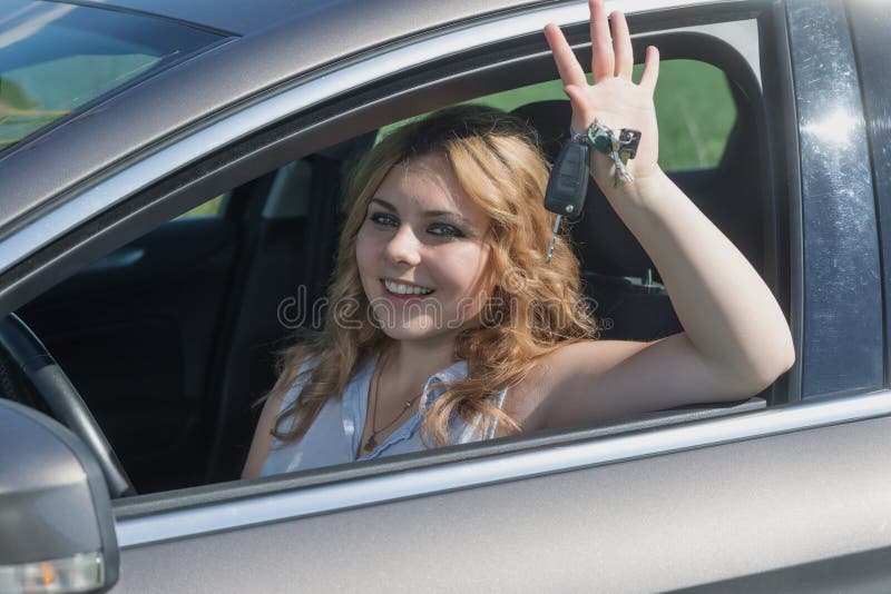 Att skratta den unga chaufförkvinnan sitter i bilen royaltyfri bild Att skratta den unga chaufförkvinnan sitter i bilen royaltyfri bild