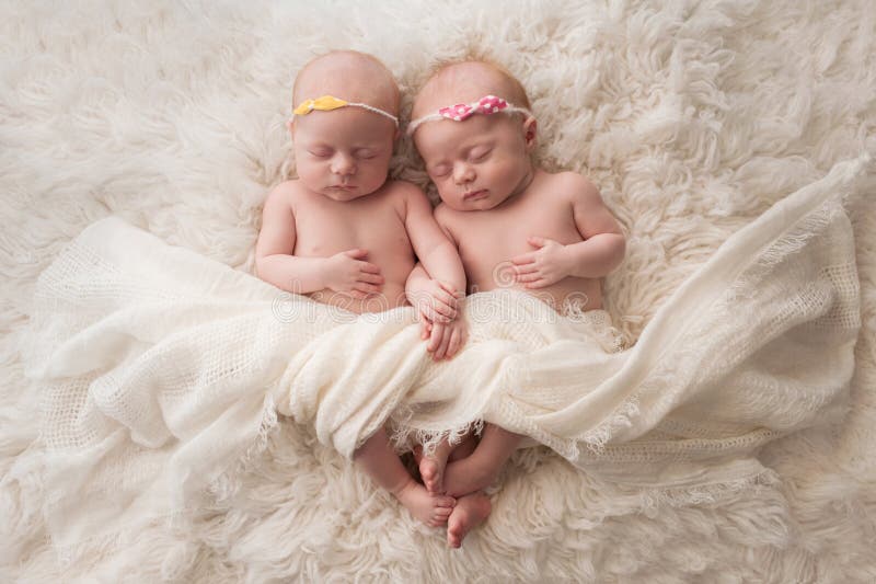 Seven week old fraternal, twin baby girls sleeping on a white flokati rug. Seven week old fraternal, twin baby girls sleeping on a white flokati rug.