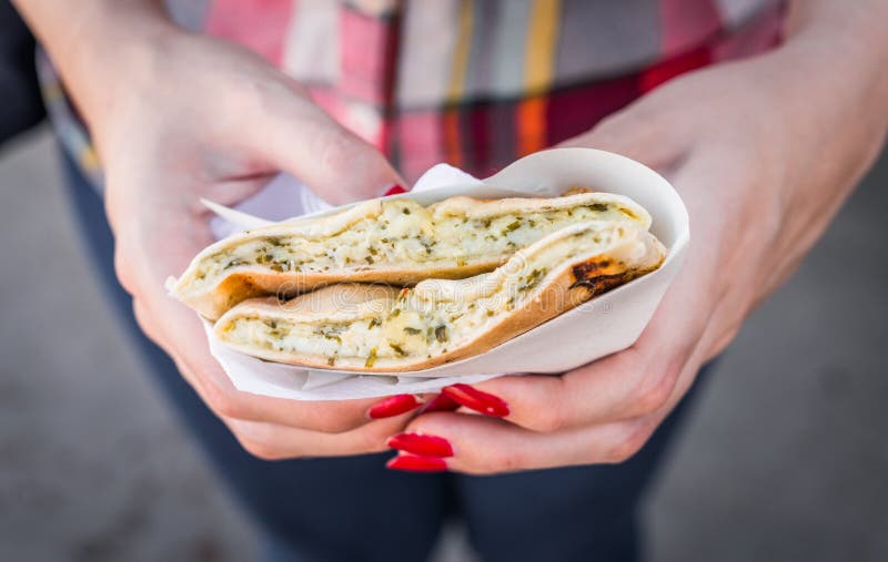 Att äta en khachapuri-smörgås med grillad smält ost på en gatulivsmedelsmarknad royaltyfria foton Att äta en khachapuri-smörgås med grillad smält ost på en gatulivsmedelsmarknad royaltyfria foton