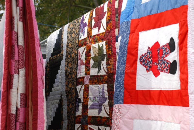 Hand made Amish Quilts hanging from a clothes line at a rural auction in Delaware. Hand made Amish Quilts hanging from a clothes line at a rural auction in Delaware.