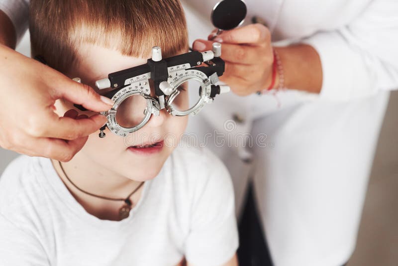 Attendi il dispositivo di sintonizzazione Bambino seduto nel gabinetto del medico e sottoposto a test di acutezza visiva immagine stock libera da diritti Attendi il dispositivo di sintonizzazione Bambino seduto nel gabinetto del medico e sottoposto a test di acutezza visiva immagine stock libera da diritti