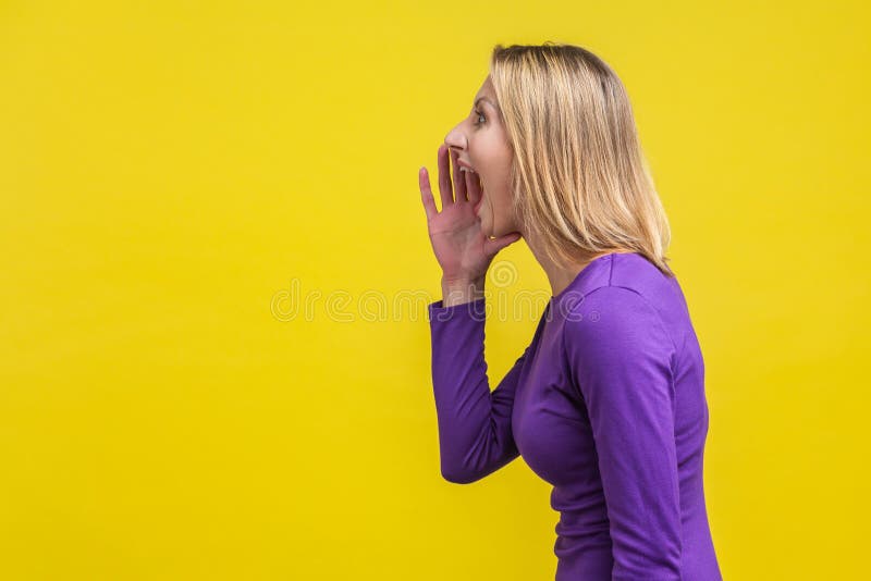 Attention! vue latérale d'une femme agressive criant une annonce sur fond jaune photographie stock