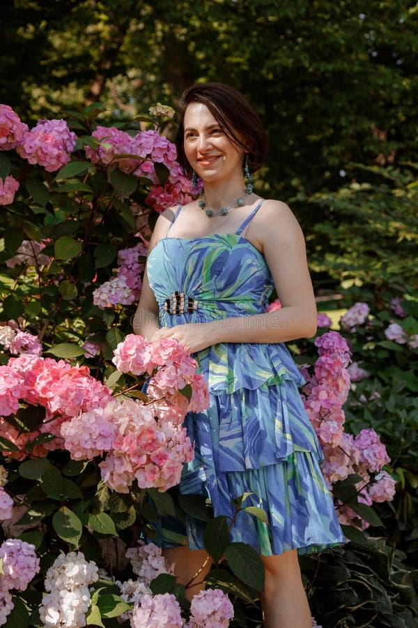 Attentionnée jeune femme heureuse entourée de fleurs. fille lancer pétales de rose. jardinage et concept de personnes. femme images stock