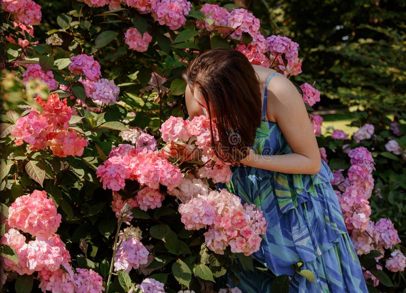 Attentionnée jeune femme heureuse entourée de fleurs. fille lancer pétales de rose. jardinage et concept de personnes. femme images stock