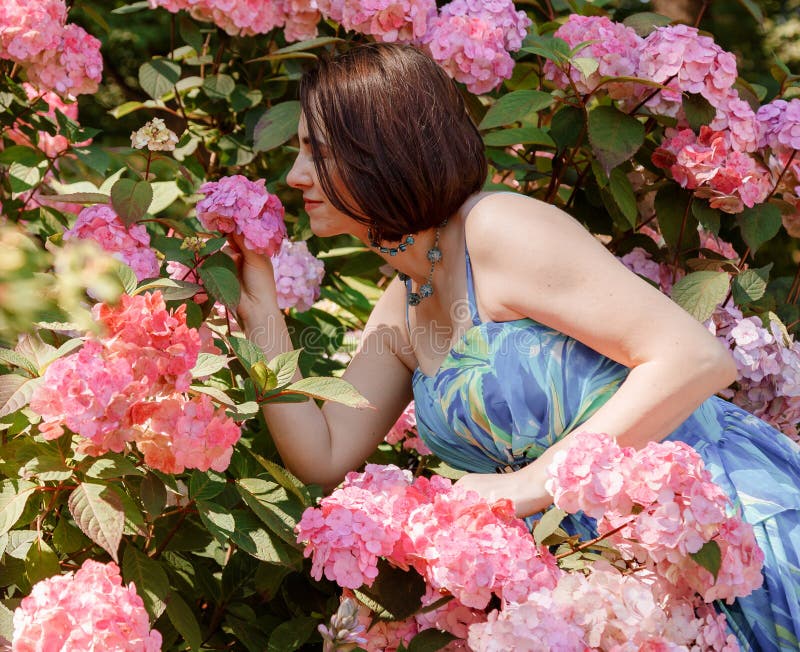 Attentionnée jeune femme heureuse entourée de fleurs. fille lancer pétales de rose. jardinage et concept de personnes. femme photos stock