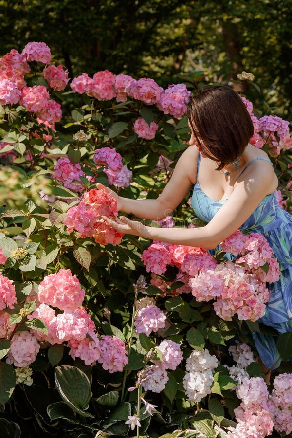 Attentionnée jeune femme heureuse entourée de fleurs. fille lancer pétales de rose. jardinage et concept de personnes. femme photo libre de droits