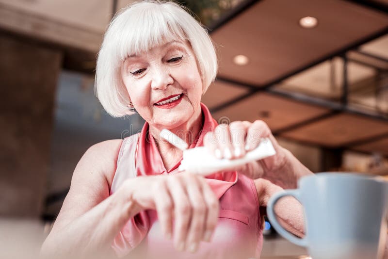 Attentive cheerful lady with bob haircut rubbing nourishing cream royalty free stock photography Attentive cheerful lady with bob haircut rubbing nourishing cream royalty free stock photography