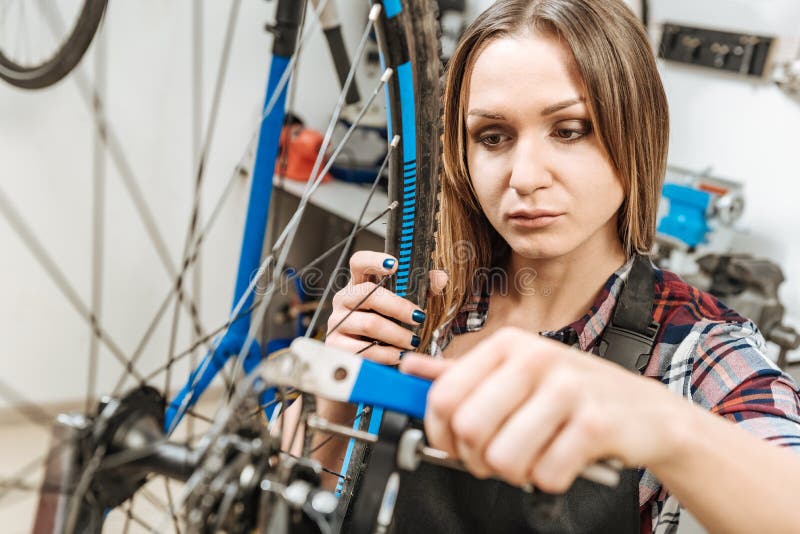 Attentive Craftswoman Fixing The Bicycle In The Garage Stock Image