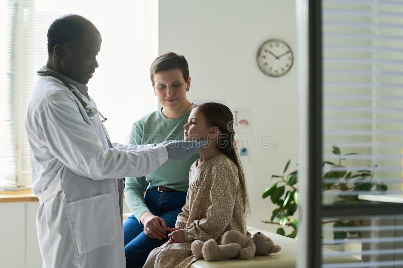 Caring Doctor Examining Child in Medical Office stock images