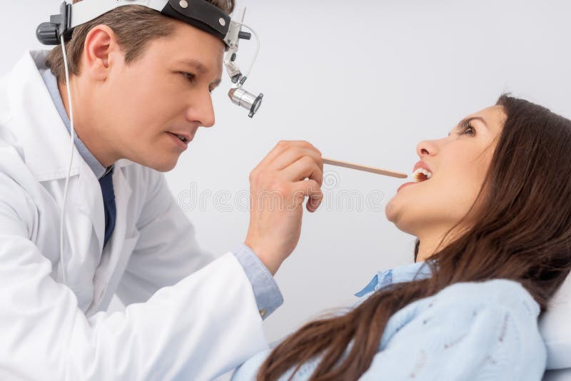 Otolaryngologist In Ent Headlight Examining Throat Stock Photo Image