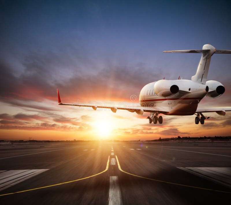 Atterrissage privé d'avion à réaction sur la piste dans la belle lumière de coucher du soleil images stock Atterrissage privé d'avion à réaction sur la piste dans la belle lumière de coucher du soleil images stock