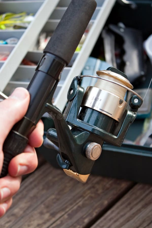 A hand holding a fishermans rod reel and tackle box ready for the start of fishing season. A hand holding a fishermans rod reel and tackle box ready for the start of fishing season.