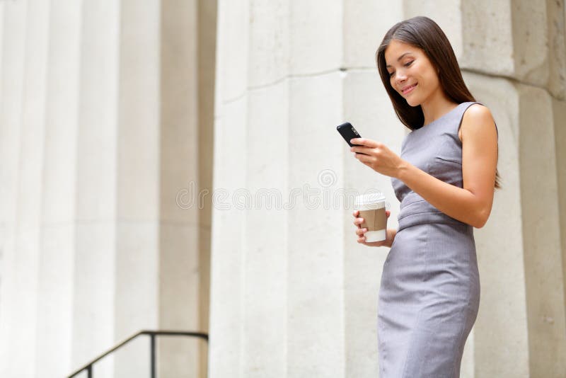 Attorney - young asian woman lawyer looking at mobile smartphone and drinking coffee from disposable paper cup. Young multiethnic female professional in the city in front of courthouse.
