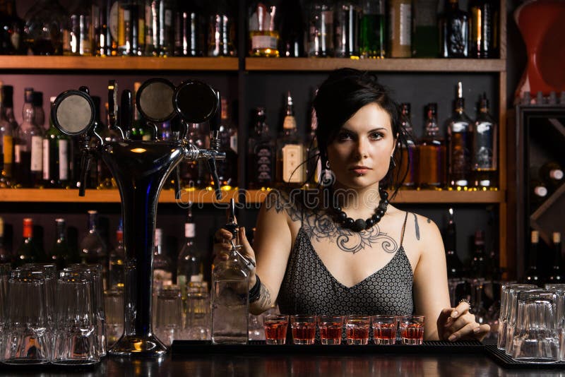 Attractive Bartender Girl Pours an Alcoholic Drink into a Glass and