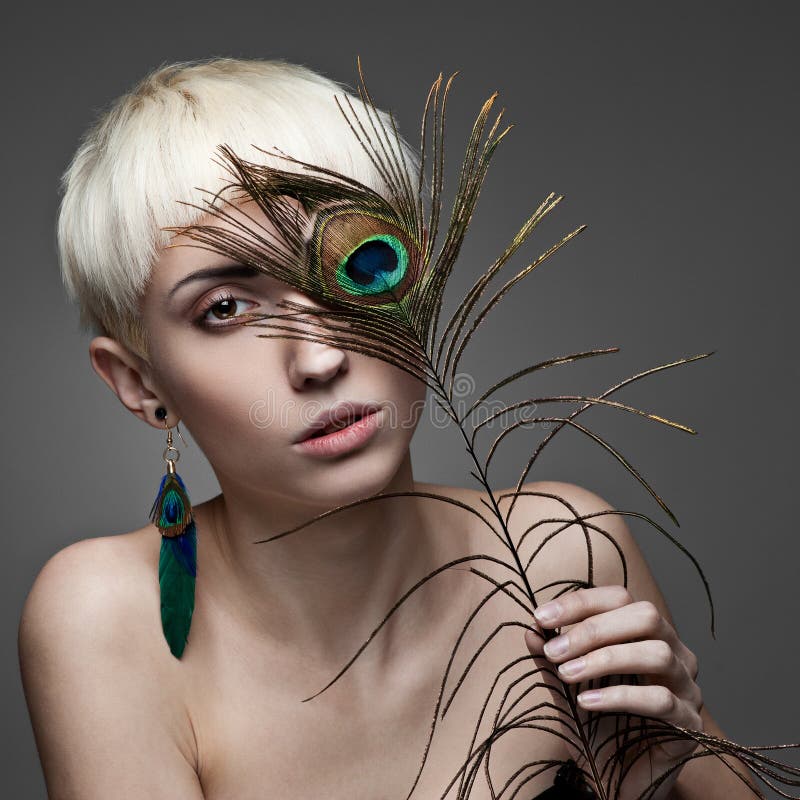 Attractive blond woman holding peacock feather