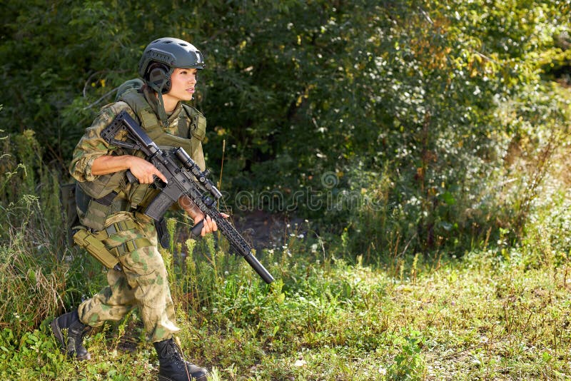 Attractive brave military woman with a gun in forest, survival in wild forest