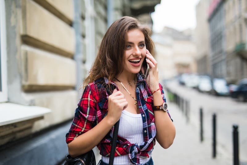 Attractive brunette young woman talking on phone while walking on city street