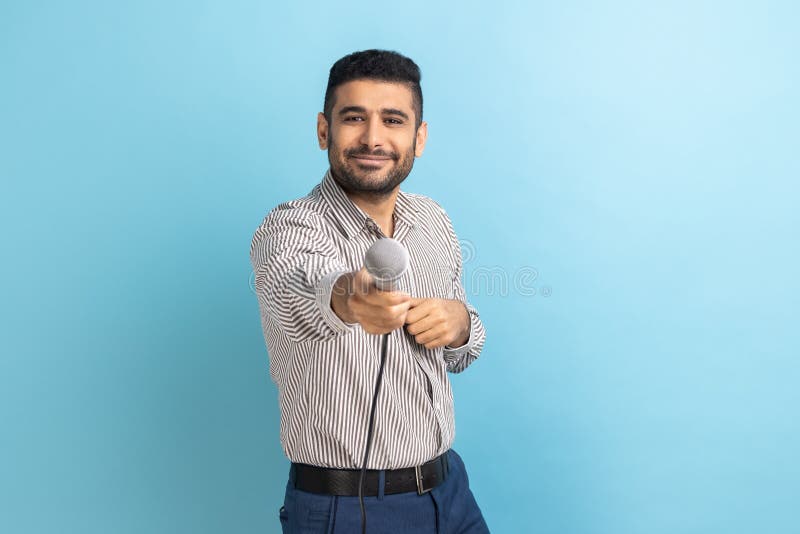 Attractive businessman with beard standing offering microphone, journalist taking interview.