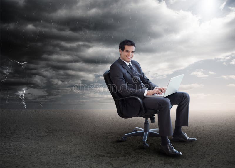 Attractive businessman using his laptop outside during stormy we