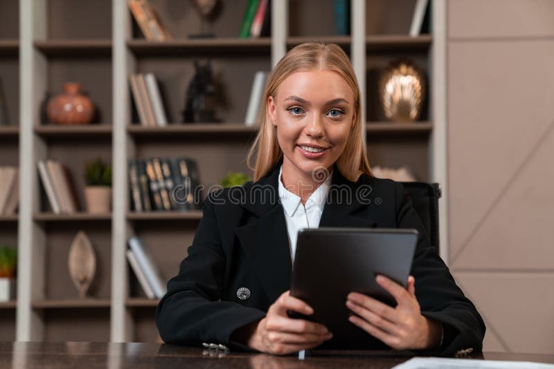 Attractive businesswoman wearing formal wear sitting typing on tablet device royalty free stock photo