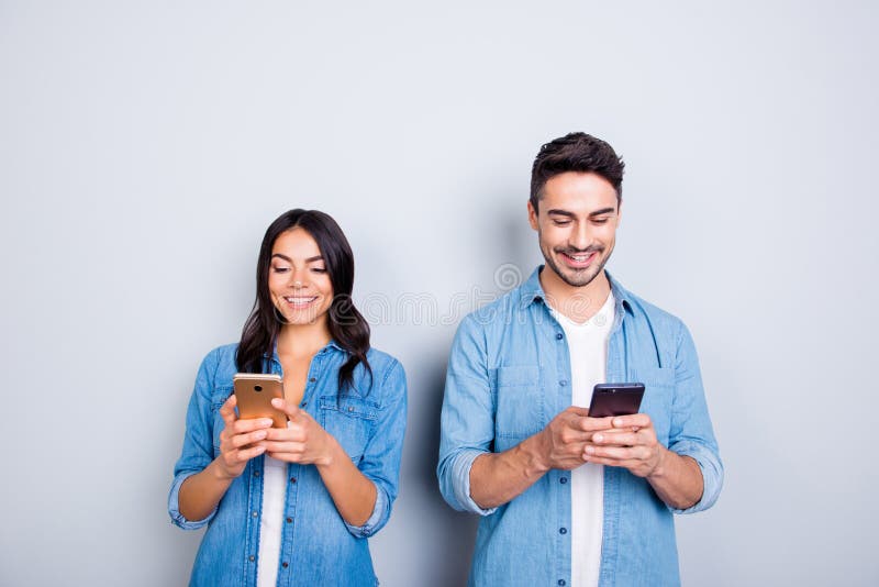 attractive, cheerful, smiling lovers in casual outfit, jeans shirts having smart phones in hands, looking at screen, texting wit stock images attractive, cheerful, smiling lovers in casual outfit, jeans shirts having smart phones in hands, looking at screen, texting wit stock images