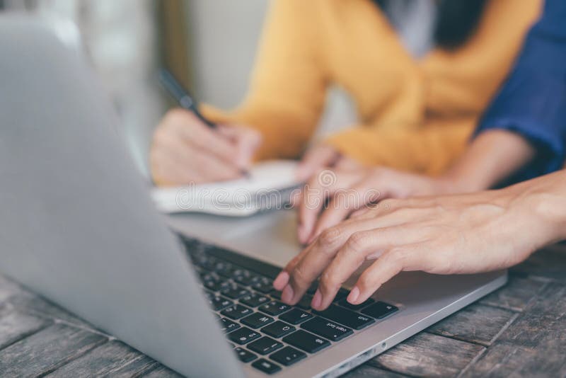 Attractive confident two business women in smart working on laptop creative in her work station. and woman hand holding a pen and stock photo Attractive confident two business women in smart working on laptop creative in her work station. and woman hand holding a pen and stock photo