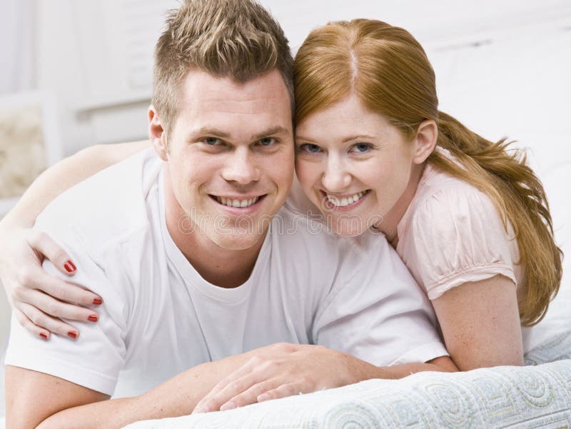 Smiling couple snuggling on bed. Square framed. Smiling couple snuggling on bed. Square framed.