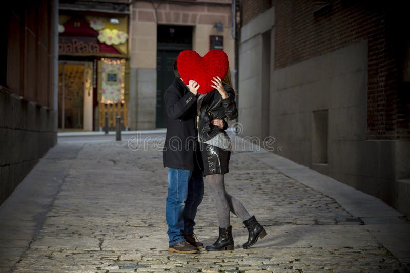 Attractive couple kissing with a red heart pillow