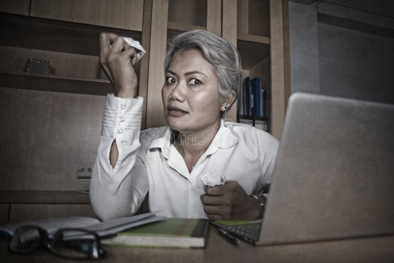 Attractive desperate and stressed middle aged Asian woman screaming gesturing overwhelmed and overwork working at office computer desk feeling exploited and upset in work stress