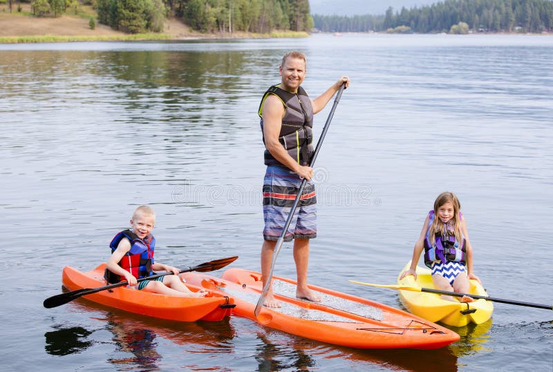 Attractive family kayaking and paddle boarding together on a beautiful lake. Attractive young family kayaking and paddle boarding together on a beautiful lake royalty free stock photos
