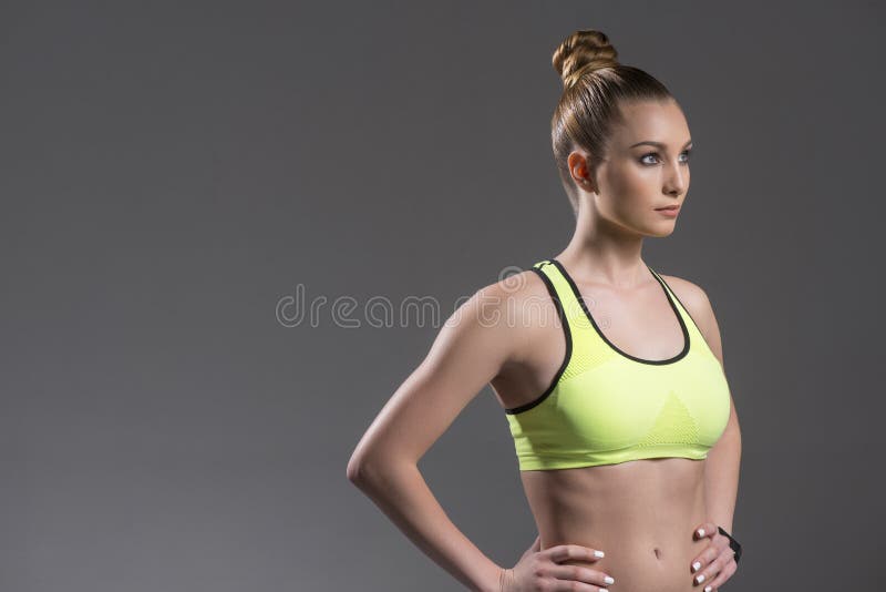 Portrait of pretty young woman going for sports. She is standing with arms akimbo. The athlete is looking forward confidently. Isolated and copy space in left side. Portrait of pretty young woman going for sports. She is standing with arms akimbo. The athlete is looking forward confidently. Isolated and copy space in left side