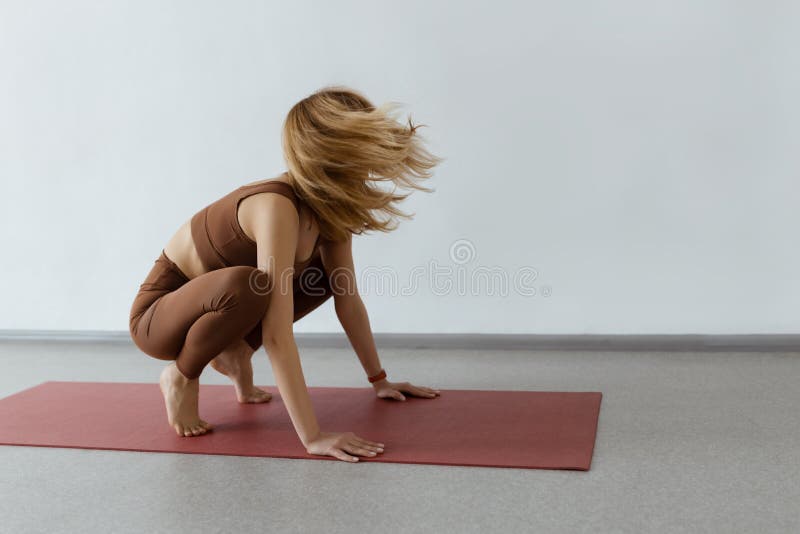 An Attractive Girl Sits on a Yoga Mat. Slim Body and Health Care