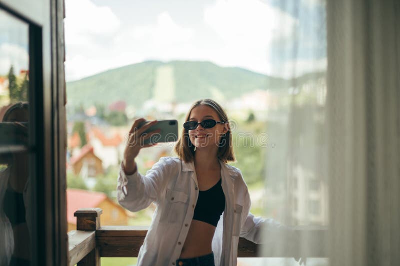 Attractive Girl Standing On The Balcony In The Apartment Taking Selfie 