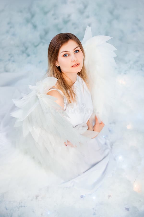 An Attractive Girl in a White Tunic with Large White Wings Behind Her ...