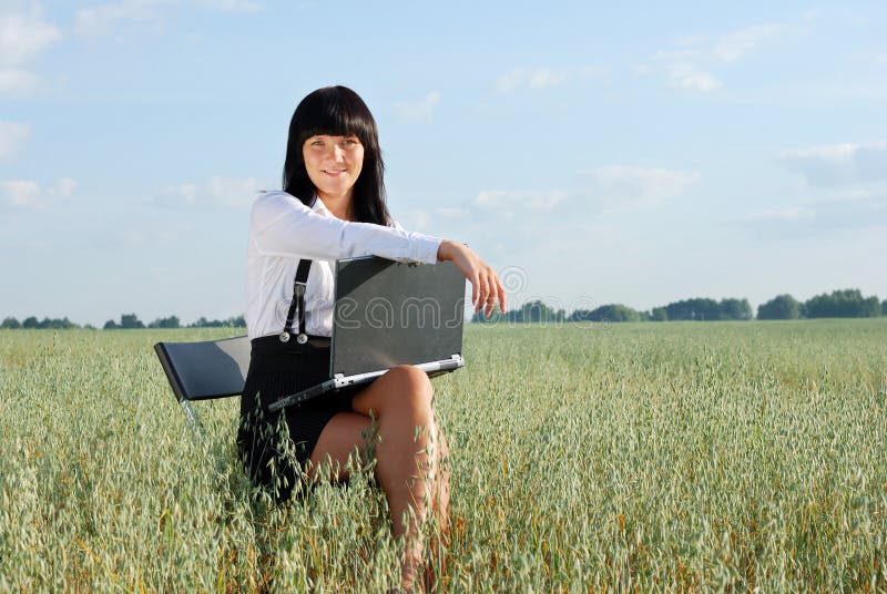 Young attractive girl with laptop on rural field. Young attractive girl with laptop on rural field