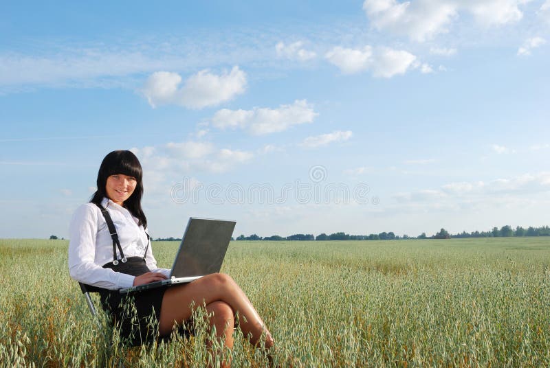 Young attractive girl with laptop on rural field. Young attractive girl with laptop on rural field