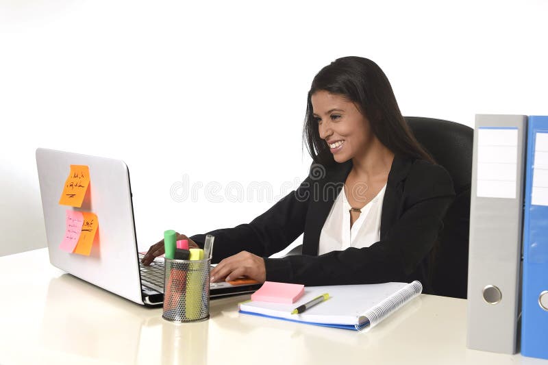 Attractive hispanic businesswoman sitting at office desk working on computer laptop smiling happy