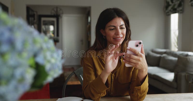 Attractive Hispanic woman using smartphone seated at table stock video