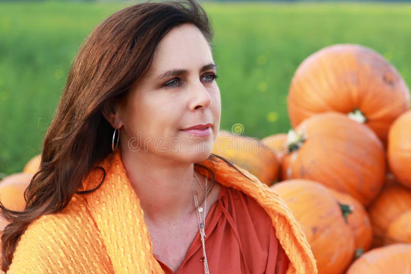 Attractive mature woman face in front of pumpkins royalty free stock photography Attractive mature woman face in front of pumpkins royalty free stock photography