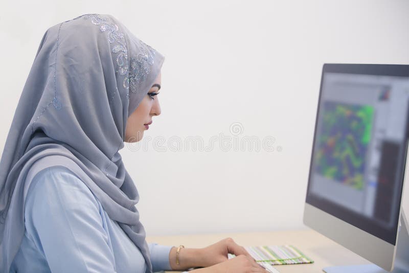 Attractive Muslim young woman working in office on computer